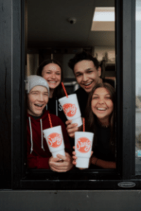 Swig employees holding drinks out the drive through window in Fairview Texas
